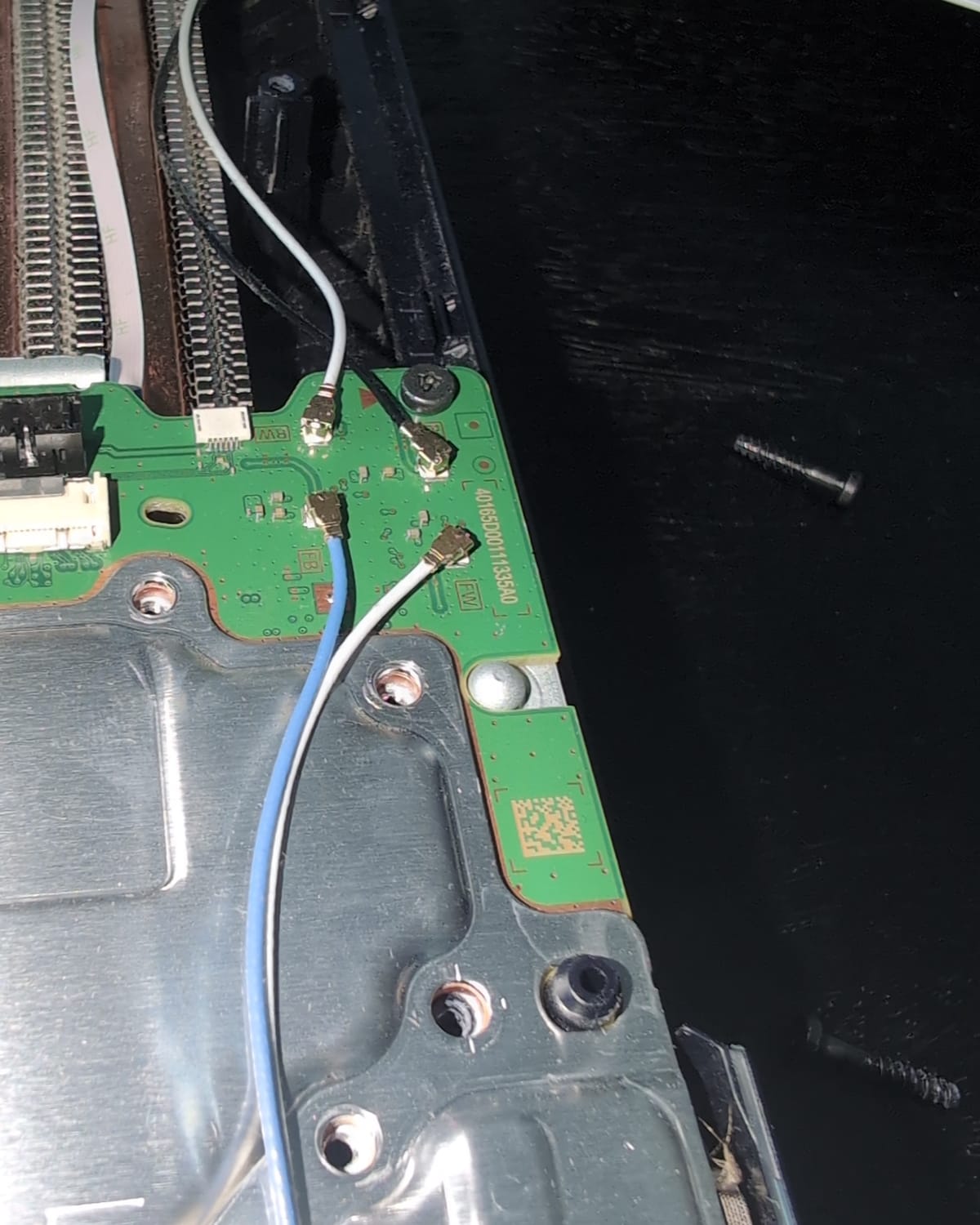 Moederbord van een PS5 open op de werkbank bij QuickChip in Almere, met het losgekoppelde netwerkprintje en de antennekabels